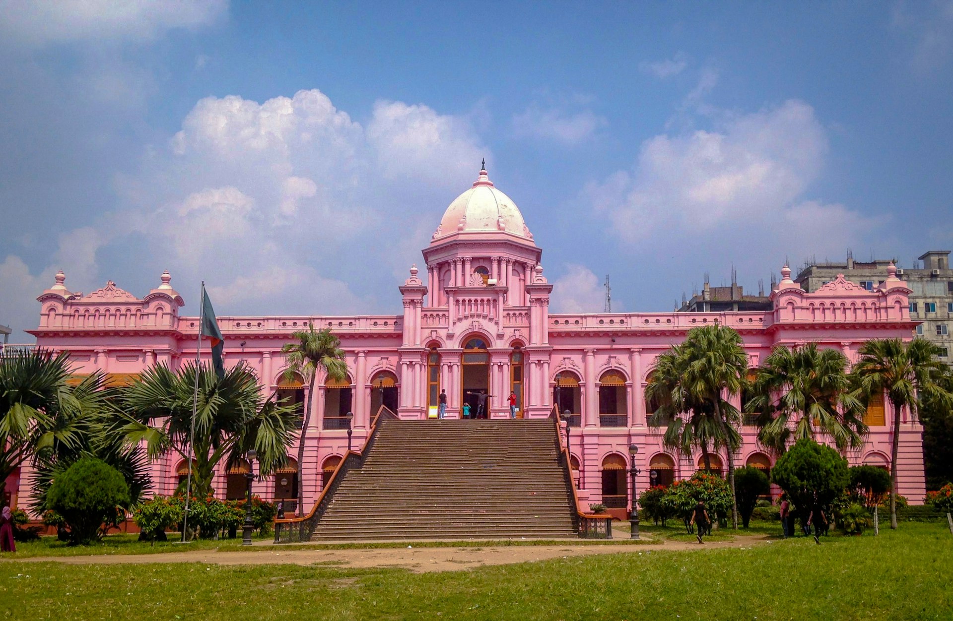 a large pink building with palm trees in front of it